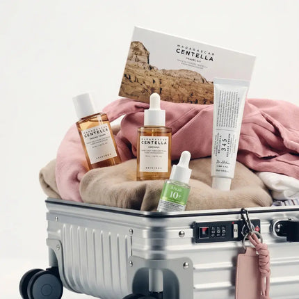 Koreaanse skincare in reisformaat op een handbagagekoffer: serums, ampullen en een zonnebrandstick