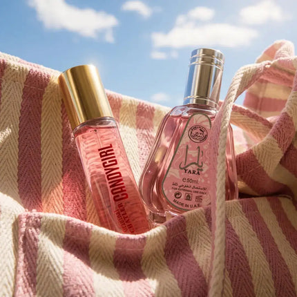 Twee parfums in reisformaat op een gestreepte handdoek in de zon, met een blauwe lucht op de achtergrond
