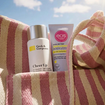 Skincare in reisformaat in een strandtas op een gestreepte handdoek: reinigingsschuim en bodylotion