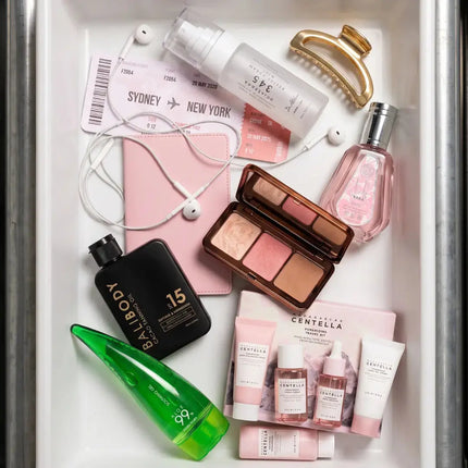Beautyproducten in reisformaat uitgestald in een metalen bak: make-up, skincare, parfum en haaraccessoires